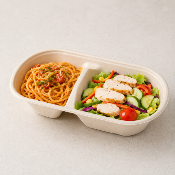 Two-compartment bagasse container with pasta, chicken and salad