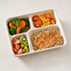 Four-compartment bagasse container filled with salmon, rice, fruit and vegetables