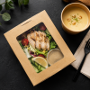 Top view of a 700ml kraft window salad box with fresh salad and soup on a dark table