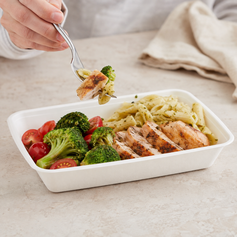 Person eating grilled chicken pasta and vegetables from a bagasse food tray